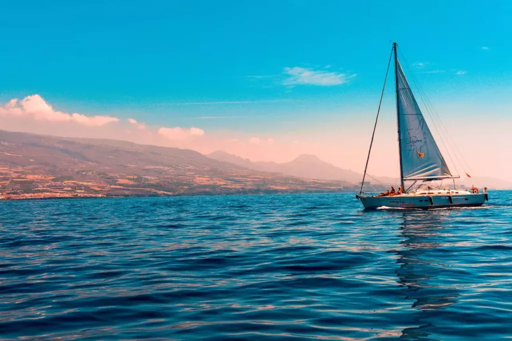 Tranquil island escape: A sailboat gracefully glides on the water near an island, encapsulating the serenity and beauty of leisurely sailing adventures.