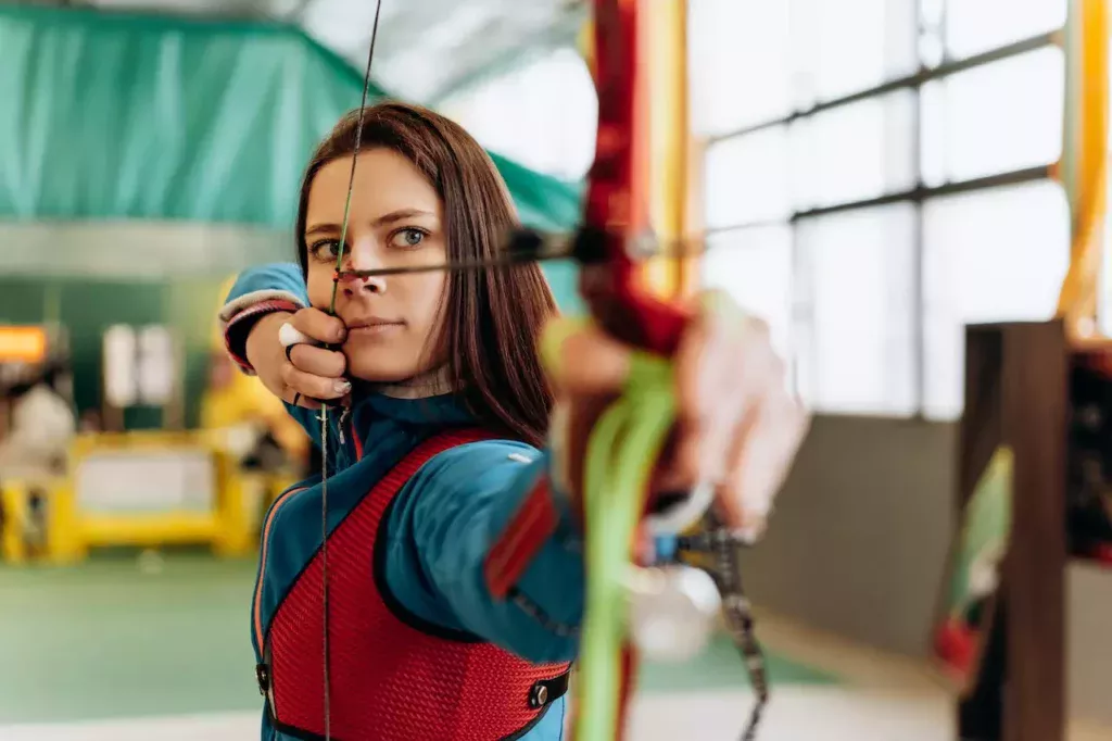 A beautiful woman confidently aiming and shooting a bow and arrow, embodying the grace and precision of archery sports.