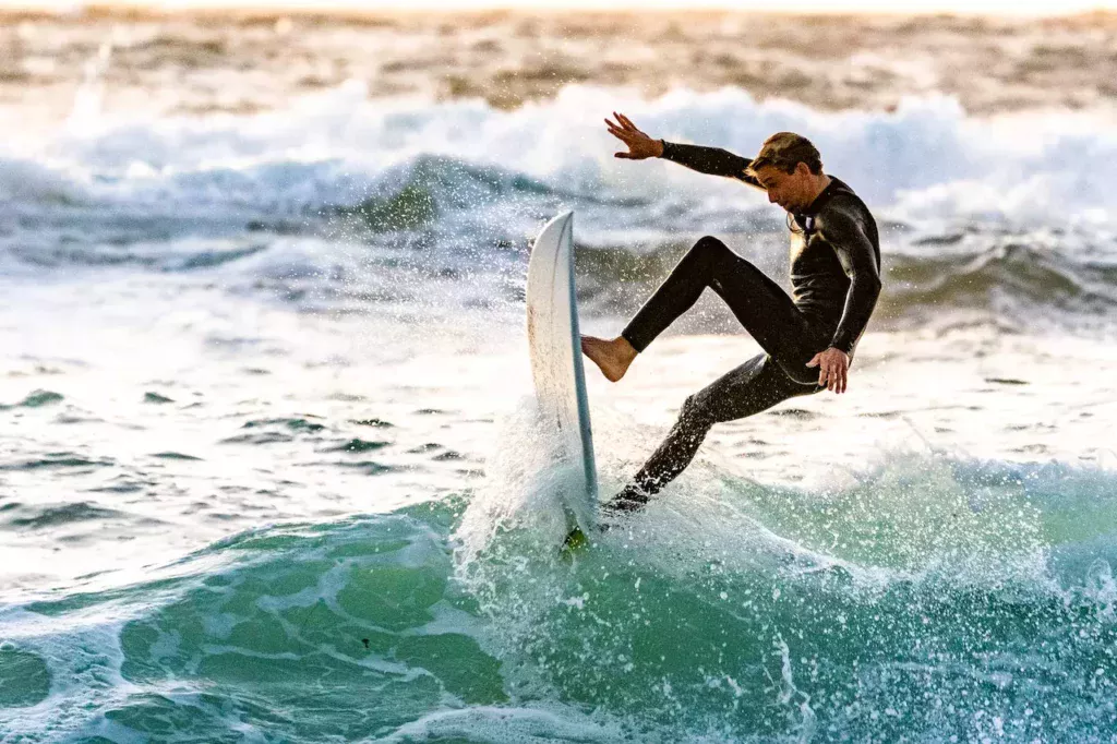 A surfer skillfully executing tricks on the waves, capturing the energy and thrill of mastering the art of surfing.